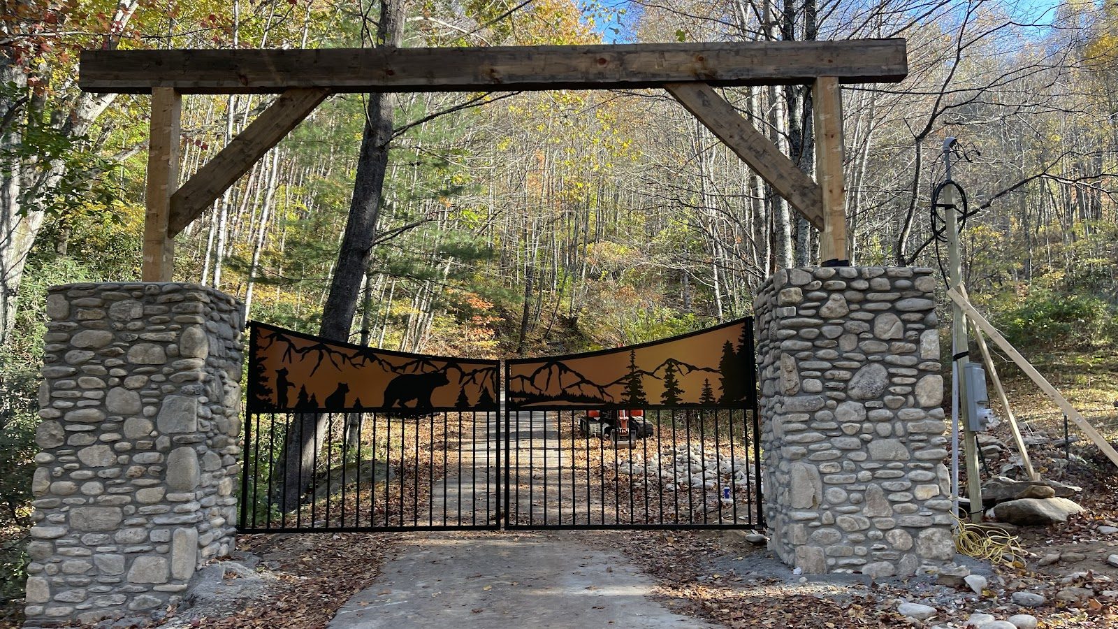 Custom entry gate between stone pillars beneath a timber arch
