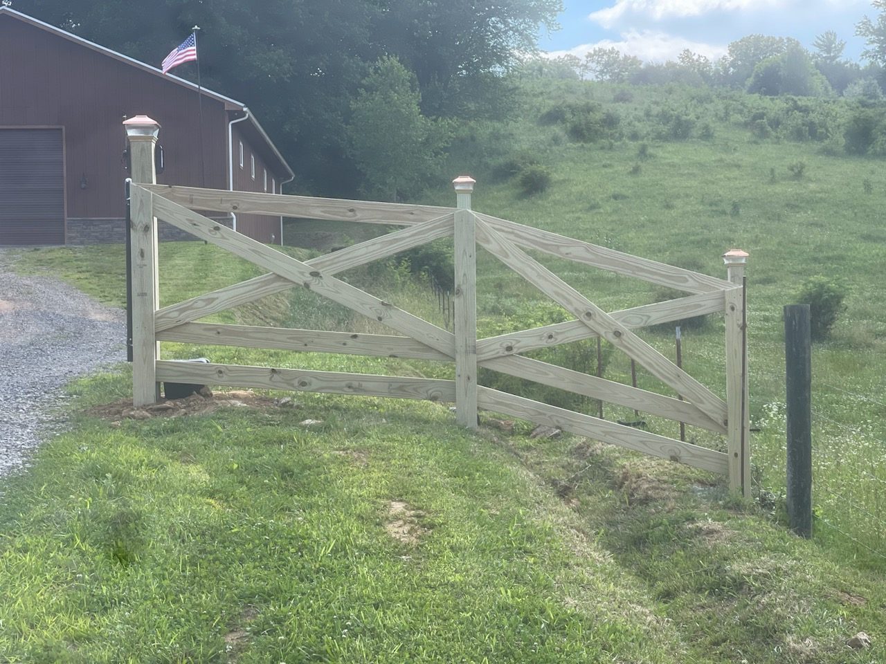 Wood cross buck farm gate beside a pasture