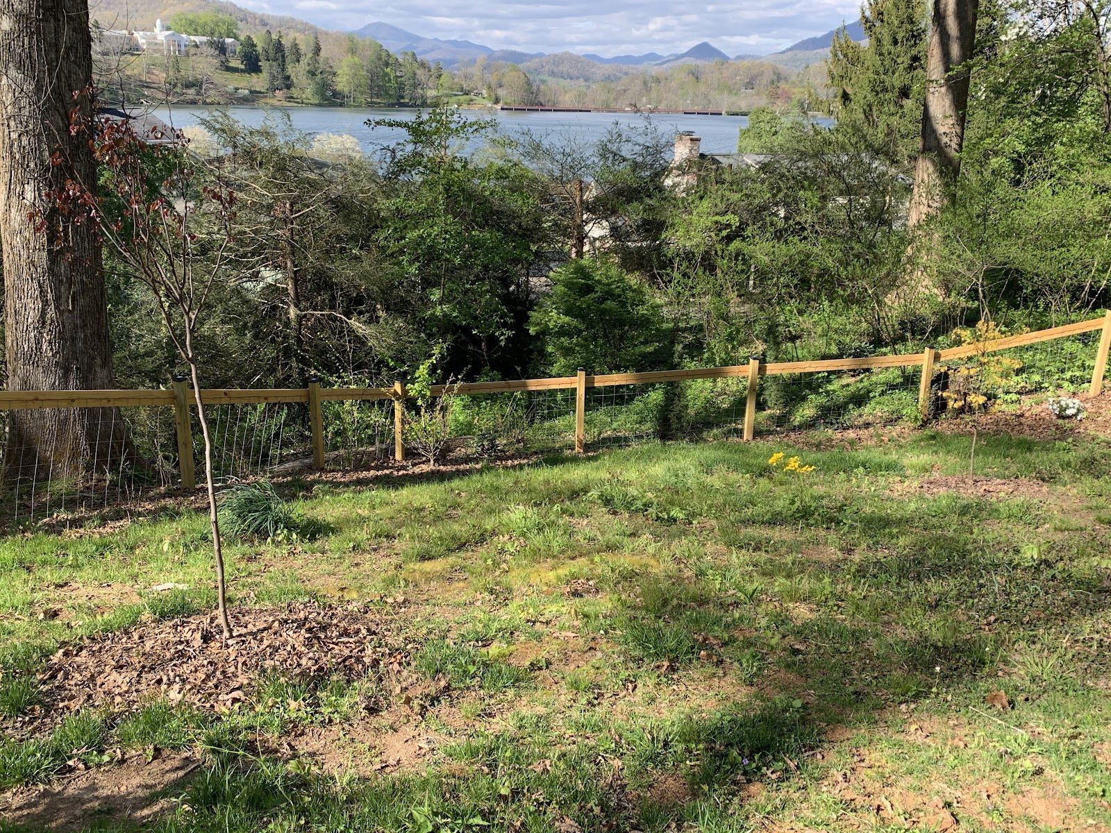 Wire-backed split rail fence on a hillside overlooking a lake